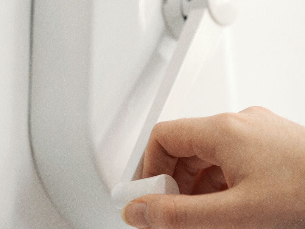 A hand is shown adjusting a wall-mounted device with a lever in a close-up view, seamlessly integrating door automation technology.