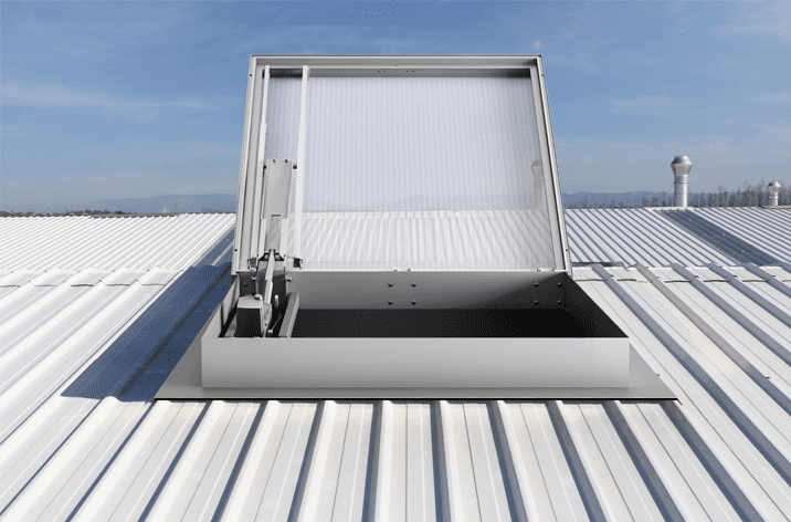 A metal roof hatch open against a clear blue sky, revealing a rectangular opening with mechanical hinges, window actuators, and support structures.