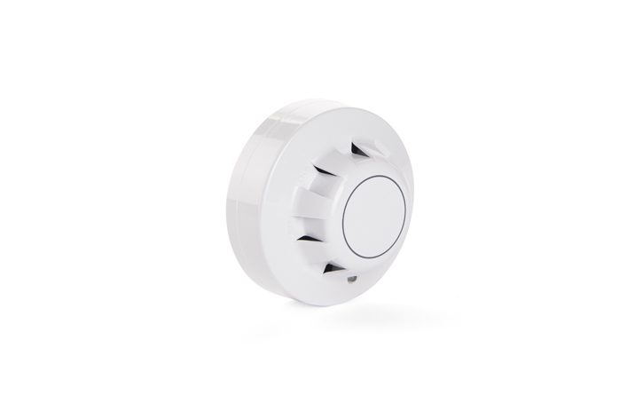 White smoke detector with circular design, featuring a central button and vent-like openings around the perimeter for optimal smoke ventilation, mounted on a white background.