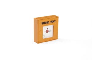 A yellow smoke vent emergency button mounted on a white wall, used to release smoke from a building in case of fire and assist with natural ventilation.