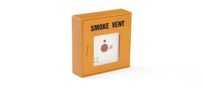 A yellow smoke vent emergency button mounted on a white wall, used to release smoke from a building in case of fire and assist with natural ventilation.