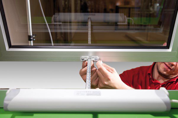 An engineer completes the final connection of fitting a window actuator